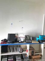 Multiple electronics displayed on shelves including JBL headphones, Samsung tablet, Amazon Echo Spot boxes, Sony speakers, wireless headset, and chargers.