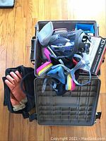 Open grey ammo container with 3M full and half face respirators, gloves, ear protection, goggles, and disposable wipes inside.