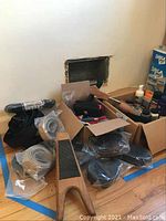 Overview of the lot showing belts, shoe care items, shoe stretcher, and laces packed around in boxes and on the floor.