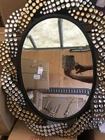 Oval wall mirror with black frame and concentric rings of faceted acrylic gems, photographed leaning against boxes