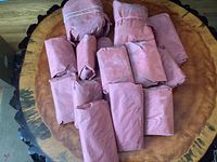 Butcher paper wrapped frozen beef cuts displayed on round wooden surface