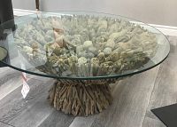 Front view of round glass-top coffee table with sculptural driftwood base