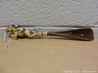 Side view of the wooden shoe horn with horse and jockey handle showing detailed carving and paint