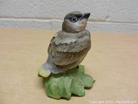 Porcelain bird figurine detailed view showing natural colors and leaf base.