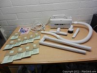 Oreck XL vacuum cleaner with hose, wand attachments, vacuum bags, and various tool accessories laid out on table.