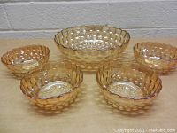 Front view of 5-piece amber bubble glass bowl set with one large scalloped bowl in the back center and four smaller bubble patterned bowls in front