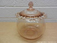 Side view of the vintage pink glass bowl with lid showing ruffled edge and finial handle