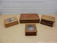 Front top view of four vintage wooden jewelry boxes showing decorative floral inlays and drawer compartments
