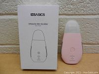 Front view of pink EZBasics Ultrasonic Skin Scrubber alongside white packaging box showing branding and model info.