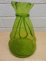 Front view of vintage handmade green glass vase with decorative loops