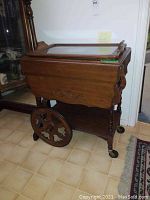Antique wood tea wagon front side view showing tray top and large wooden wheel on one side