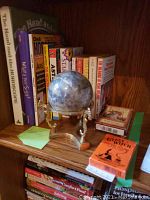 Shelf with astrology and horoscope books, mounted stone globe on brass stand, and two decks of fortune-telling cards visible