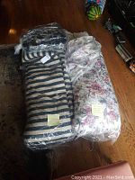 Photo showing two comforters wrapped in plastic, one floral and one striped, with notes indicating they are dry-cleaned.