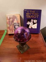View of the purple glass globe mounted in bronze stand with tarot card sets behind showing titles