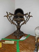 Full view of a black onyx globe sitting on an ornate metal stand with floral and scrollwork designs.
