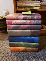 Stack of 7 hardcover Harry Potter books showing spines and dust jackets with fantasy artwork.