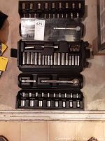 Complete ratchet and socket set displayed in black plastic case showing multiple socket sizes and ratchet wrench