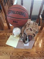 Lot displayed on wooden table showing baseball, glove, and basketball together