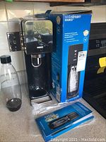 Image showing SodaStream Source soda maker, bottle, original blue box, and instruction manual.