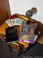 Photo showing two Tarot books, a deck of Tarot cards, and a decorative glass orb on a metal stand on a wooden table.