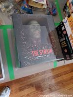 Photo of The Strain DVD collector set showing embossed creature face with horror artwork in black and red.
