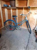 Side angle showing full blue vintage Raleigh bike with step-through frame, black saddle, and rear fender