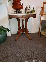 Full front view of the table showing single drawer and carved base