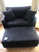 Front view of black microfiber loveseat and storage ottoman with two matching throw pillows