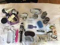 Top-down view of assorted bathroom and beauty items including toothbrush, hairdryers, mirrors, soap dispensers, hair pick, curling iron, sleeping masks, and reading glasses.