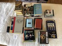 Photo showing stack and spread of 28 books of varying genres including paperbacks, antique and art books as well as Hitsville USA Motown Singles collection box set