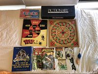 Full display of the lot items on a white cloth background, showing the various game boxes, boards, comics, and joke toys.