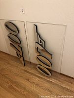 Two 3D James Bond 007 logos attached on clear acrylic panels leaning against a wall, showing overall look and size.