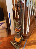 Full view of Dyson DC25 Ball vacuum cleaner in gray and orange with scuff marks.