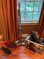 Full view of Euroflex Monster SC60 canister vacuum with hose and floor head, Dirt Devil handheld vacuum and Shark Steam Mop SK460 upright unit on hardwood floor near window.