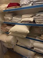 Multiple folded sheet sets and pillows on three-tier wire shelving