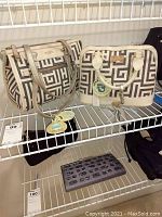 Two matching Spartina purses with cream and gray geometric pattern, displayed on a wire shelf