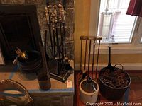 Fireplace area including fireplace tools on stand, metal basket with pine cones, stone jug