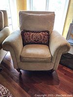 Front view of beige Paul Robert armchair with rolled arms, back cushion, and patterned throw pillow.