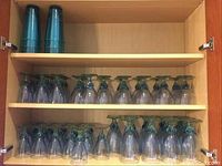 Two stacks of three translucent teal plastic cups on wooden shelf