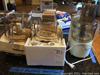 Photo of both food processors with bowls and accessories on box and counter.