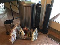 Full view of all items including two air purifiers, two trash cans, ironing board cover, irons, and furniture sliders.