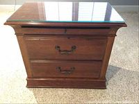 Front view of the wooden nightstand showing two drawers, metal handles and glass top.