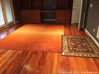Photo of living room floor showing the larger rust orange 8x11 area rug and smaller 4x6 traditional patterned rug side by side on wood flooring.
