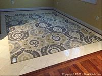 Full view of ivory, graphite, and yellow patterned area rug installed on tiled floor in room