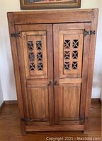 Front view of solid wood cabinet showing doors, decorative cutouts, and hardware