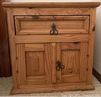 Front view of the pine solid wood bedside cabinet showing one drawer and two door cabinet with metal ring pulls.