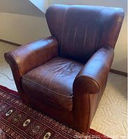 Front angle view of brown leather armchair showing overall condition