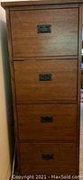 Full front view of the solid oak four drawer filing cabinet showing wood grain and metal drawer pulls.