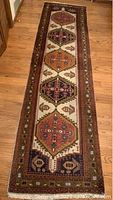 Full view of oriental wool carpet runner laid on hardwood floor, showing overall medallion pattern and proportions.