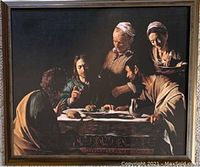 Frontal photo of framed Caravaggio 'Supper at Emmaus' print with visible reflections on glass